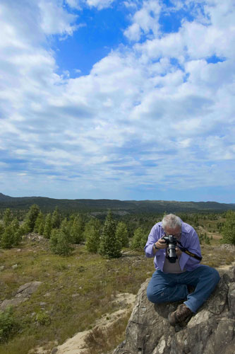 A photo of a guy taking a picture with the sky in the background.