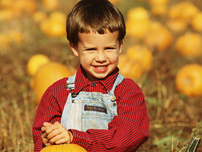 A picture of a young boy in a pumpkin patch.